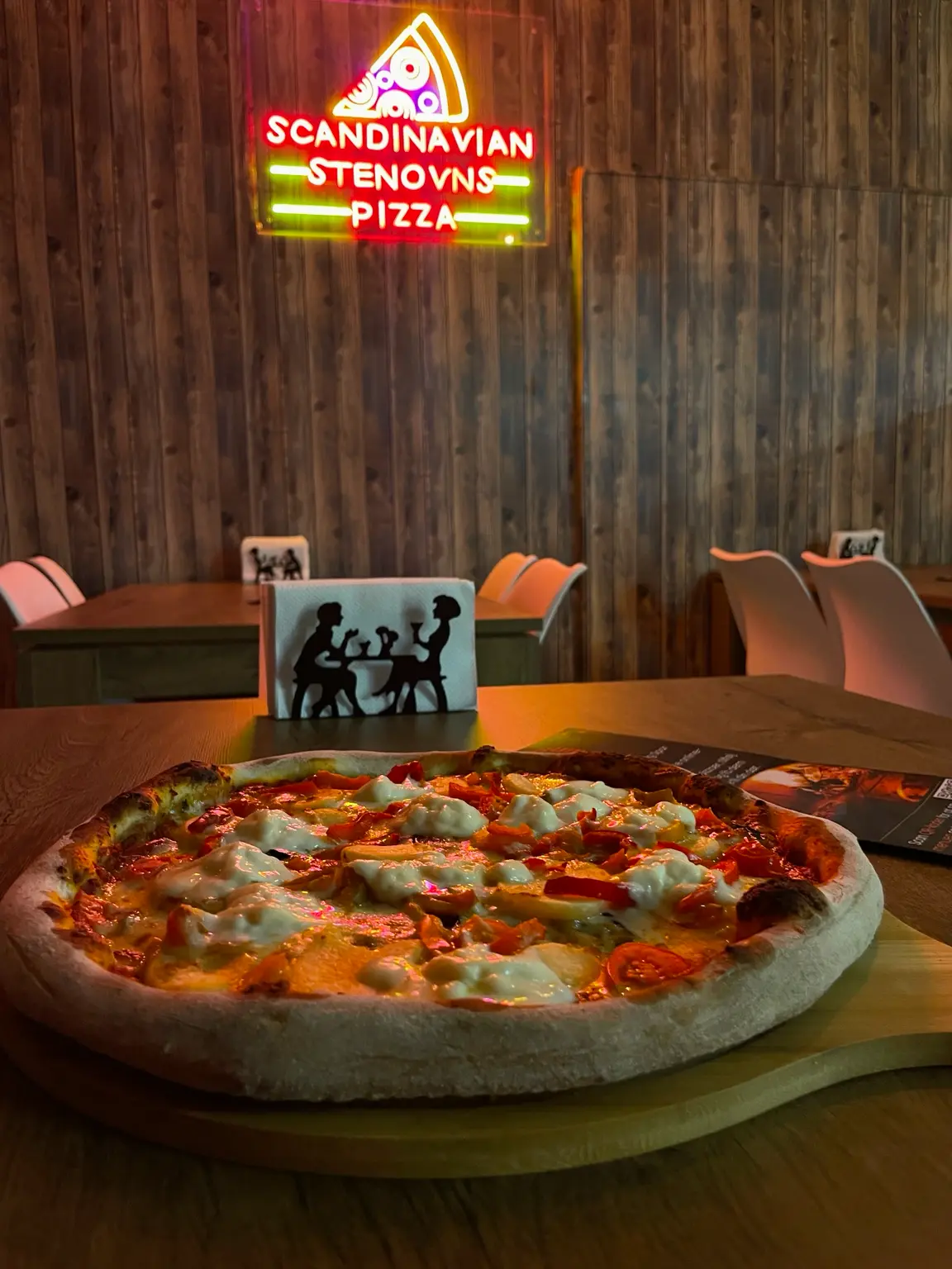 Frisklavet stenovnspizza på bordet i restauranten under neonskiltet Scandinavian Stenovns Pizza i Horsens